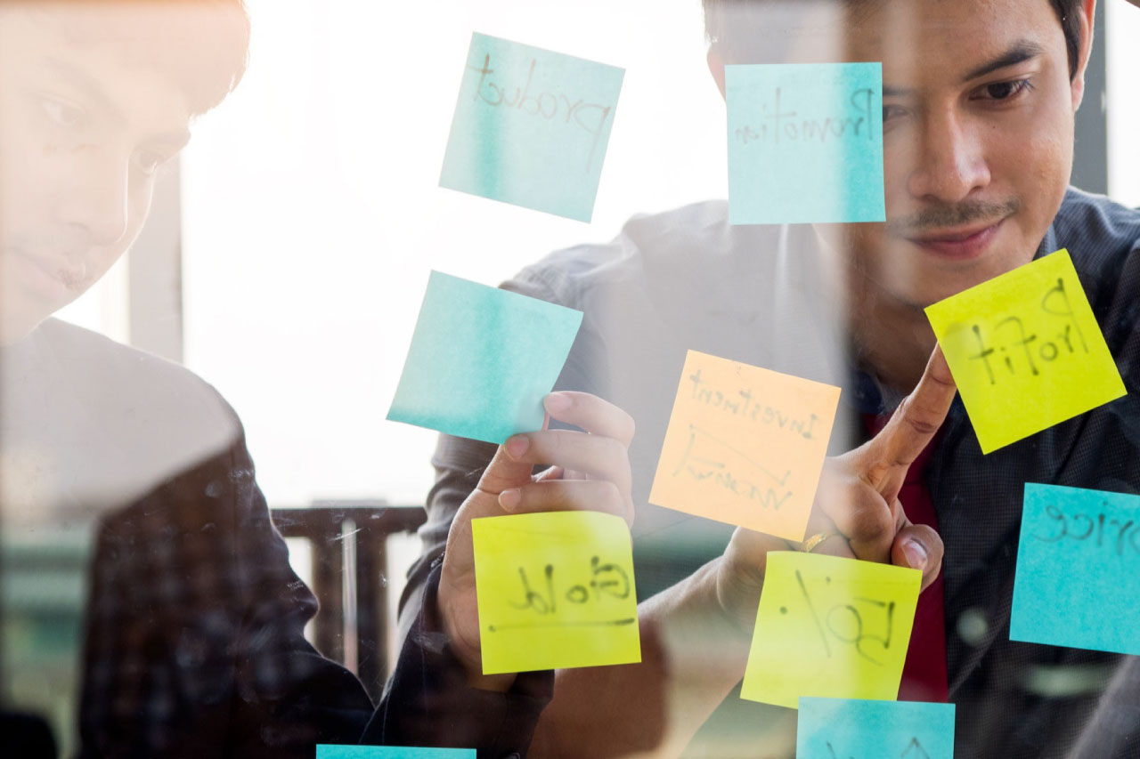 Business owner with his partner pointing to a sticky note.